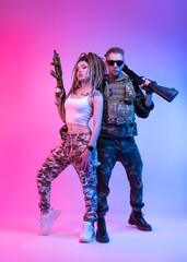 daring stylish girl with an automatic rifle and a guy in military clothes with an airsoft gun in...