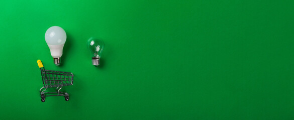 Led lamp in shopping car on isolated green background. Flat lay. Concept ecology, save planet...