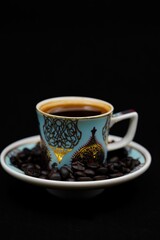 Close-up of black coffee in a blue cup with intricate golden designs on it