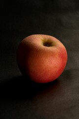Vertical closeup of a red apple on a dark background