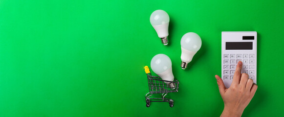 incandescent lamp and hand hold led lamps against on isolated green background. Energy efficiency...