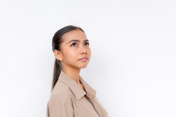 Portrait of a confident young Filipino woman looking slightly up, standing isolated over a white...
