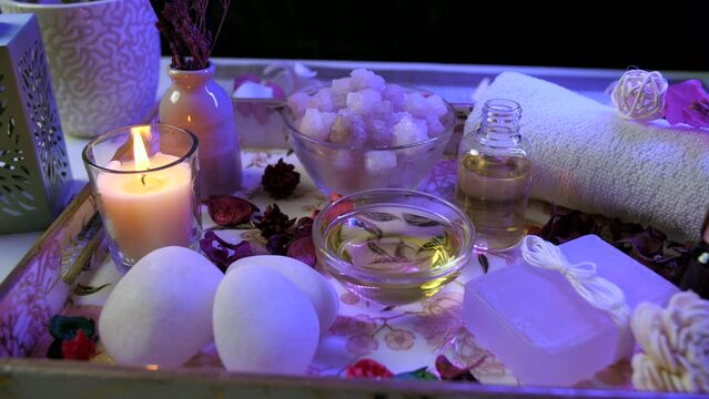 Beautiful spa composition with stones  almond oil and scented candles in led lighting setup - dark interior  body care. Relaxing surroundings for customer appointment by a body care parlor with aes...