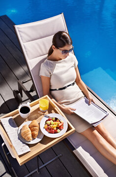 Breakfast, Documents And Business Woman Poolside, Reading Information On Work Trip From Above. Food, Paper And Woman Employee Sitting Outdoor At Hotel Swimming Pool For Contract Review Or Hospitality