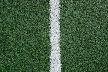 Texture of artificial grass with white line, green football field surface, close-up. Design element...