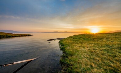 Landscape of a lake surrounded by a grassy shore during a beautiful sunrise