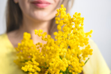 Beautiful young woman with mimosa flowers on white background
