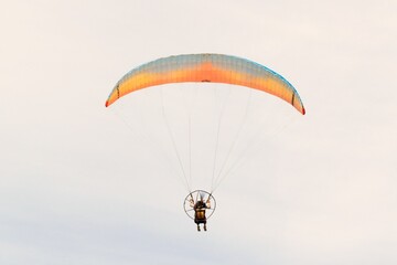 Man paragliding, soaring across a bright blue sky and enjoying the liberating feeling of freedom