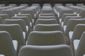 Closeup of a modern white auditorium filled with rows of chairs under the natural light