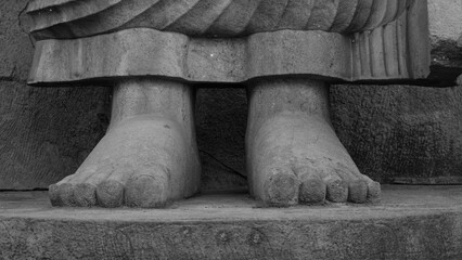Grayscale shot of the feet of a stone statue of Buddha.