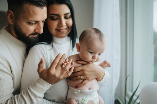 Mother and father with cute baby boy spending leisure time at home