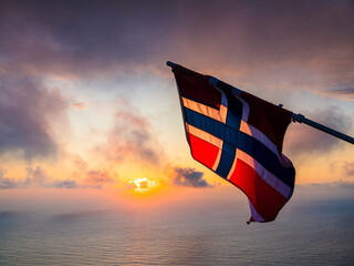 Flag of Norway against moody sky with setting sun
