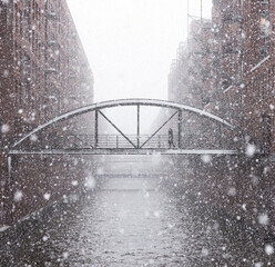 Hamburg, Germany: snow falling over the city buildings with  bridge in winter