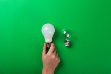 Idea male hand touch LED light bulbs on green color background. Flat lay with copy space. Concept...