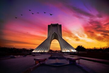 Sky illuminated with golden and orange hues over Azadi Tower in Tehran, Iran