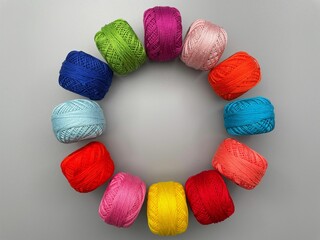 Colorful balls of wool arranged in a circular pattern on a gray background