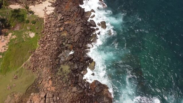 Drone view over sea waves covering a rocky coast in Dondra, Sri Lanka