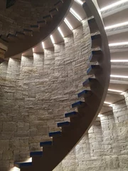 Foto op Canvas Interior shot of a stone wall featuring a staircase with illuminated spiral steps © Wirestock