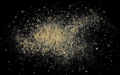 Close up ground white pepper, scattered isolated on black, macro