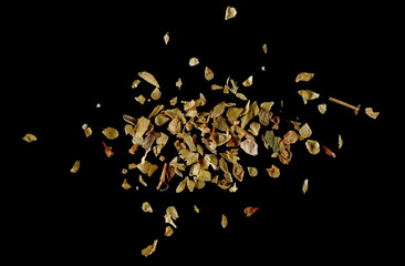 Close up oregano dry chopped, scatter isolated on black, macro