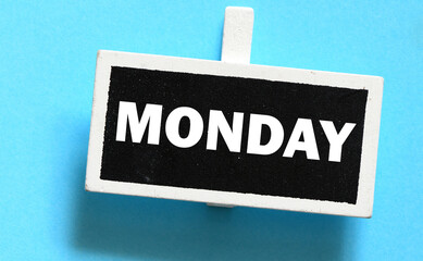 The word MONDAY on a small chalk board over a blue background.