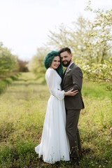 a bearded groom and a girl with green hair are walking