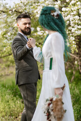 a bearded groom and a girl with green hair dance and twirl
