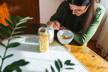 A young woman eating corn flakes for breakfast in the morning in her apartment 