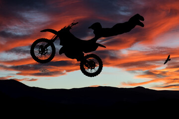 Silhouette of motocross rider at sunset. Extreme sports and twilight.