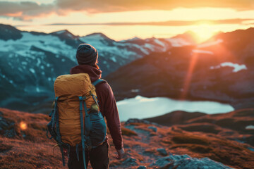Close up back view of young man with a travel backpack on his back stands on mountain at sunset. Joyful free travel concept - obrazy, fototapety, plakaty