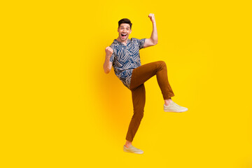 Full length photo of overjoyed crazy man dressed print shirt brown pants clenching fists yell win bet isolated on yellow color background