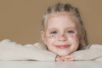 Portrait of cute little blonde girl with boxer braids and glitters om face