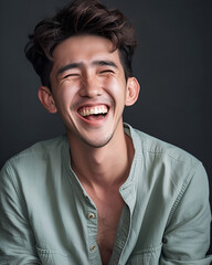 Fototapeta premium A man is laughing in front of the camera, the man is wearing a light green shirt, the background is plain dark gray