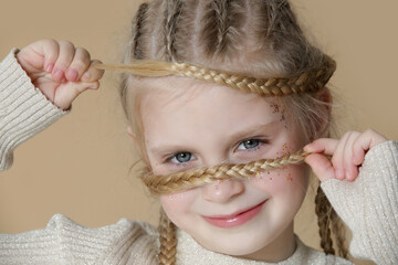 Portrait of cute little blonde girl with boxer braids and glitters om face