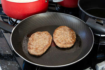 frying burger in frying pan for meal