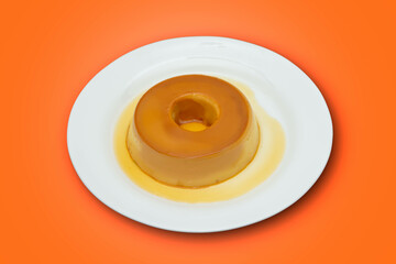 pudim de leite, or pudding also known as flan on a wooden table with metallic spoon