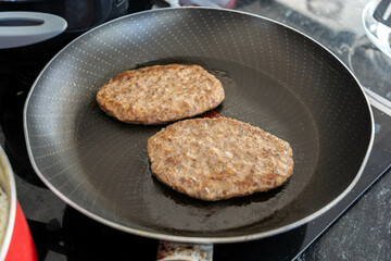 frying burger in frying pan for meal