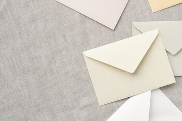 beige and white envelopes are randomly placed on a gray tablecloth, leaving a copy space on the left