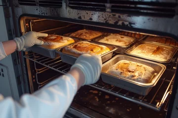 Rolgordijnen Brood baker in gloves removing hot bread pans from an industrial oven