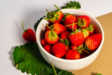 ripe red strawberries A white bowl filled with juicy, ripe red strawberries. Strawberries on brown background, white table, fresh strawberries healthy food pictures