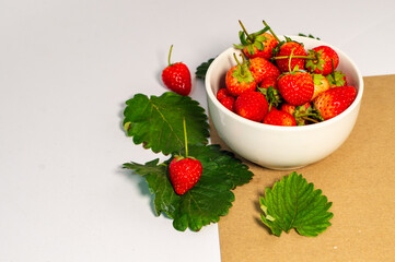 ripe red strawberries A white bowl filled with juicy, ripe red strawberries. Strawberries on brown background, white table, fresh strawberries healthy food pictures