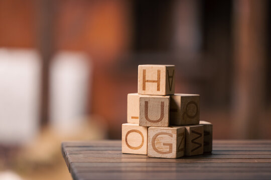 Stack of wooden building blocks with letters on blurred background with copy space
