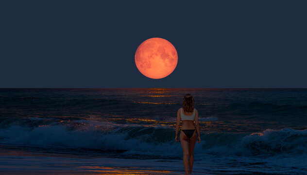 Night sky with moon in the clouds on the foreground power sea wave - Happy slim girl in red and black bikini  with raised up arms on the seashore in Alanya "Elements of this image furnished by NASA