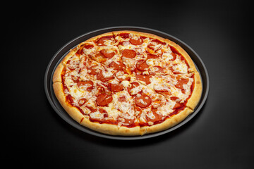 Pepperoni pizza with sausage and cheese. On a black background.