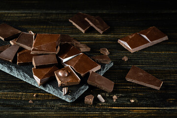 Broken pieces of chocolate bar on a dark vintage table. Free space for advertising