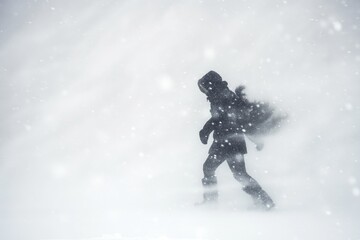 silhouetted person pushing through a blizzard