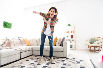 Full length photo of cheerful positive guy dressed checkered shirt listening music headphones dancing indoors house home room
