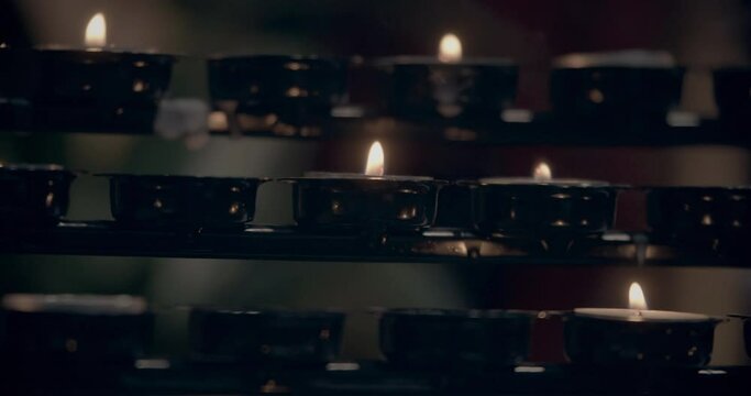Candle light. Blurred candle light in a gothic church. Cathedrals praying candles. Candle of hope in gothic catholic church from medieval time. Short little candles. Many lines of candles. Cold colors