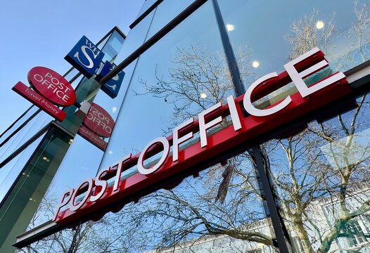 Chelmsford, UK - January 19, 2024: Low angle view of the Post Office sign on a glass-fronted building in Chelmsford High Street, Essex, England. 