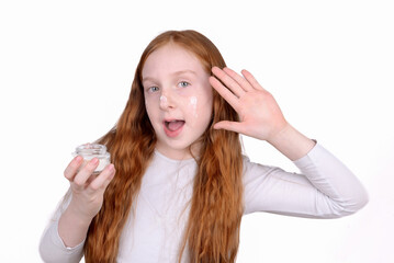 Fototapeta premium Redhead little girl with freckles uses face cream
